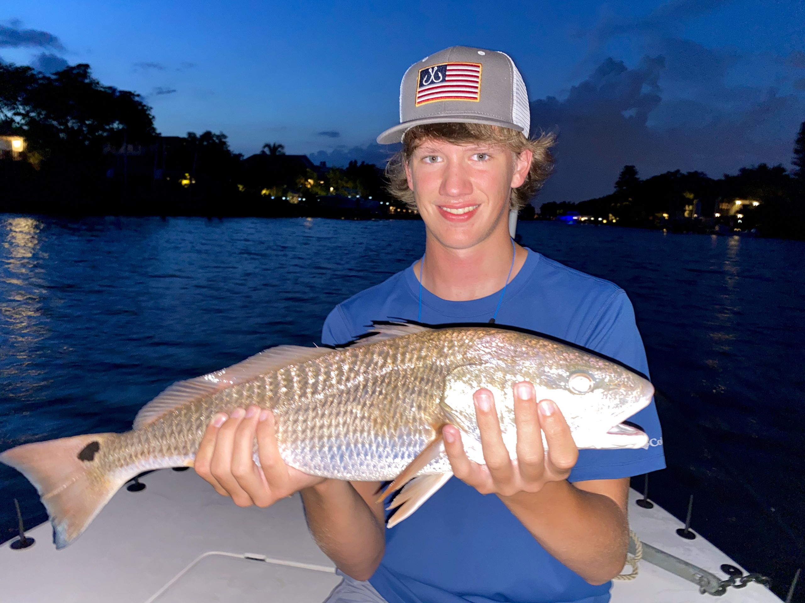A young angler holds a redfish he caught just before dark