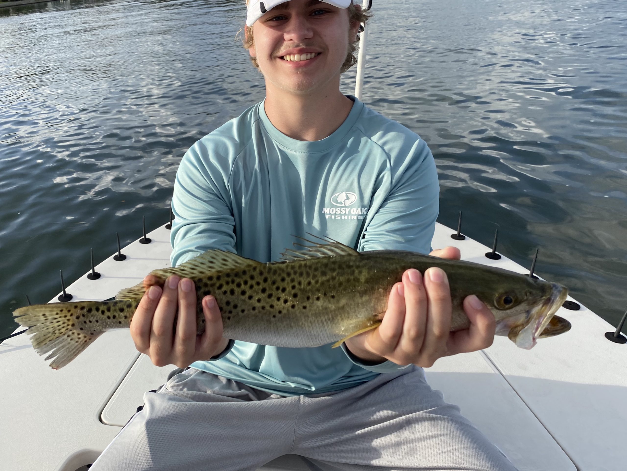 A young mustached angler holds a spotted seatrout for the camera