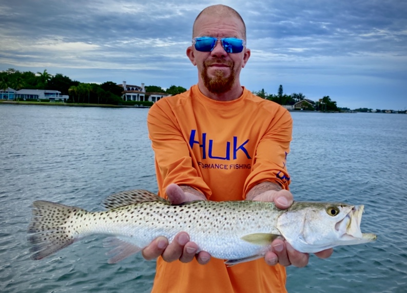 An angler holds a spotted seatrout out for the camera