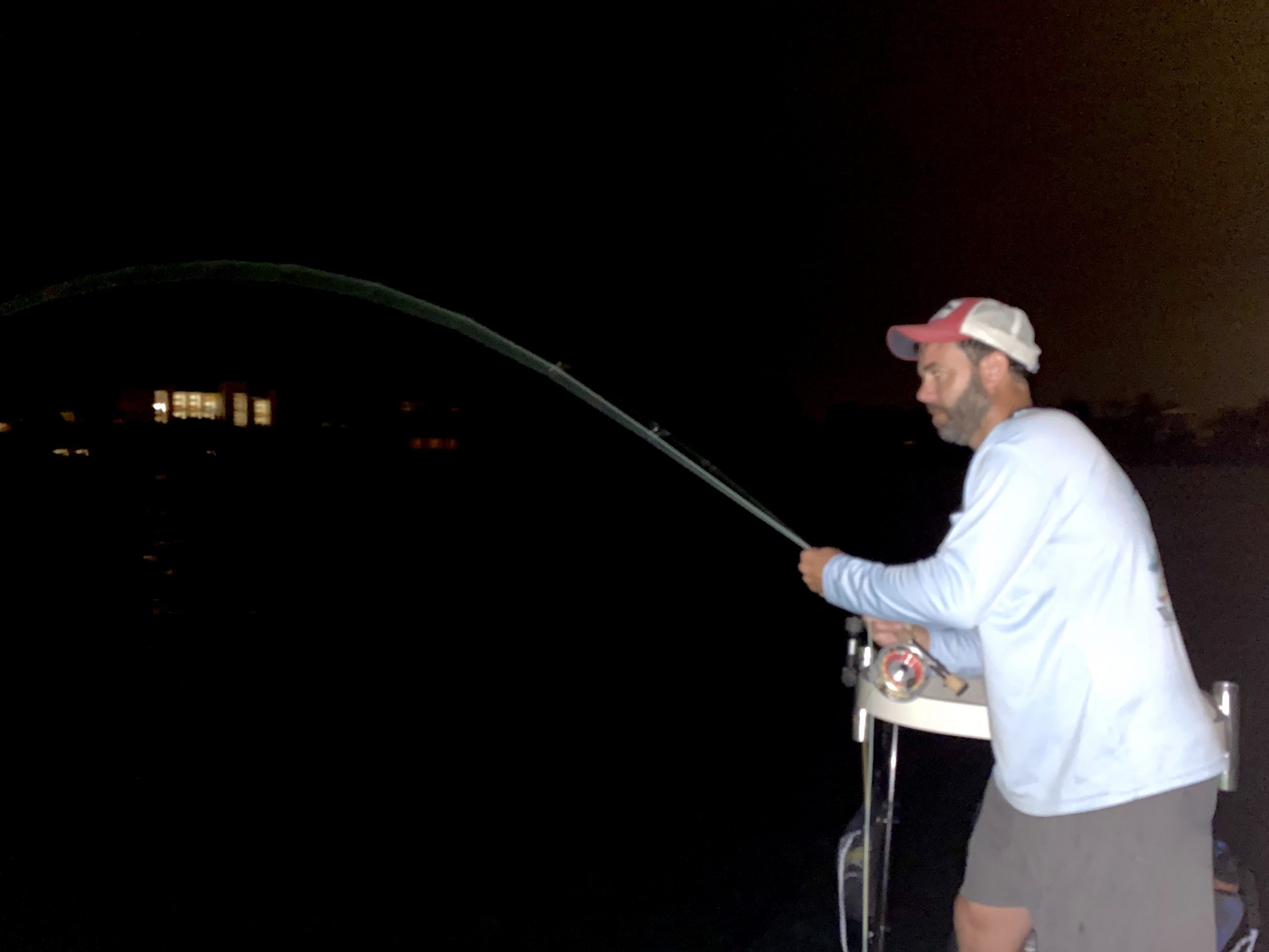 An angler fights a snook at night