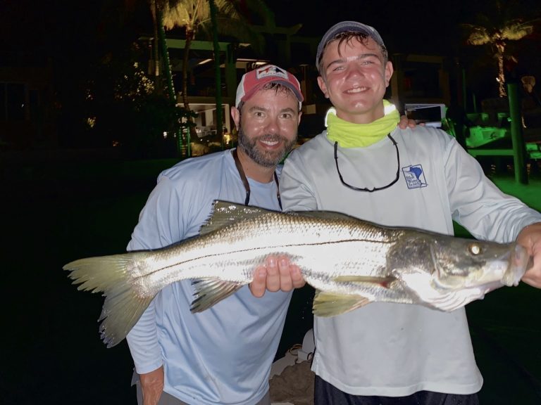 An angler and his son hold a big snook for the camera