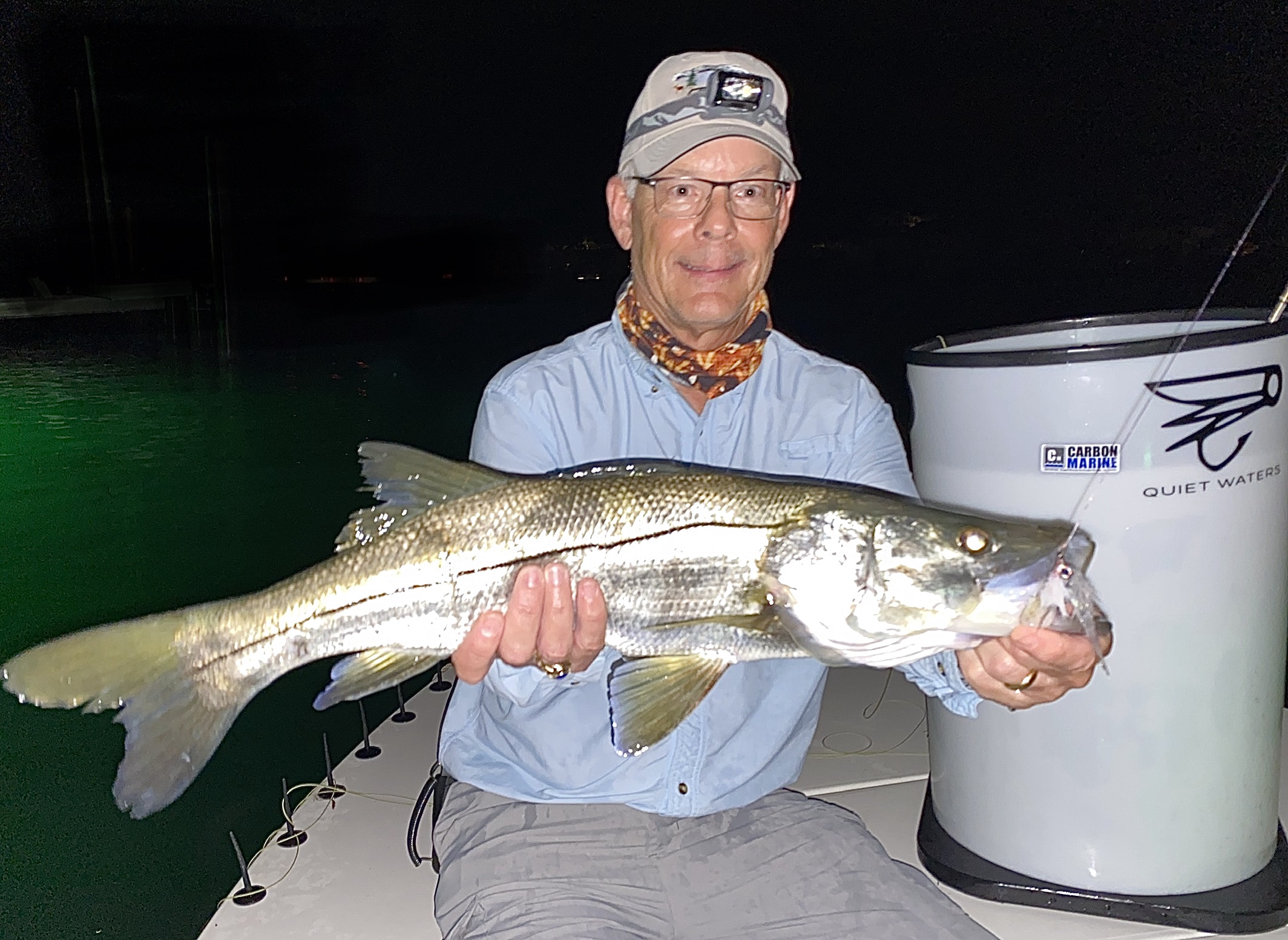 An angler holds his snook up for the camera on the bow of the boat