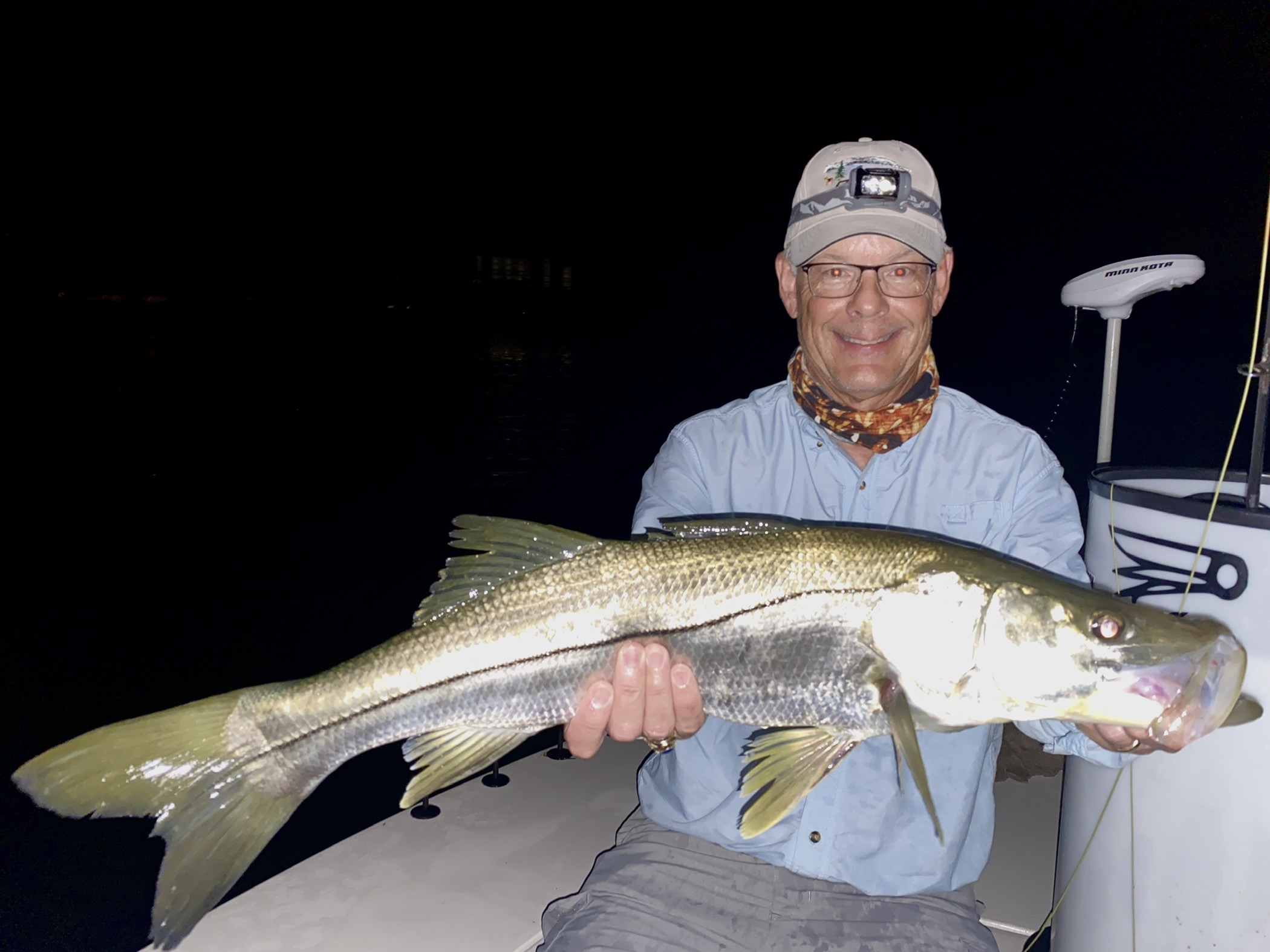 An angler smiles holding a large snook