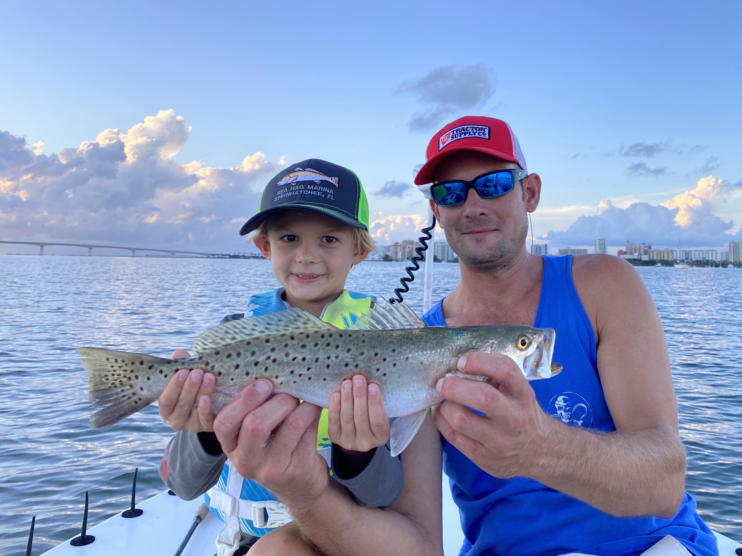 An angler and his dad hold a seatrout up for the camera