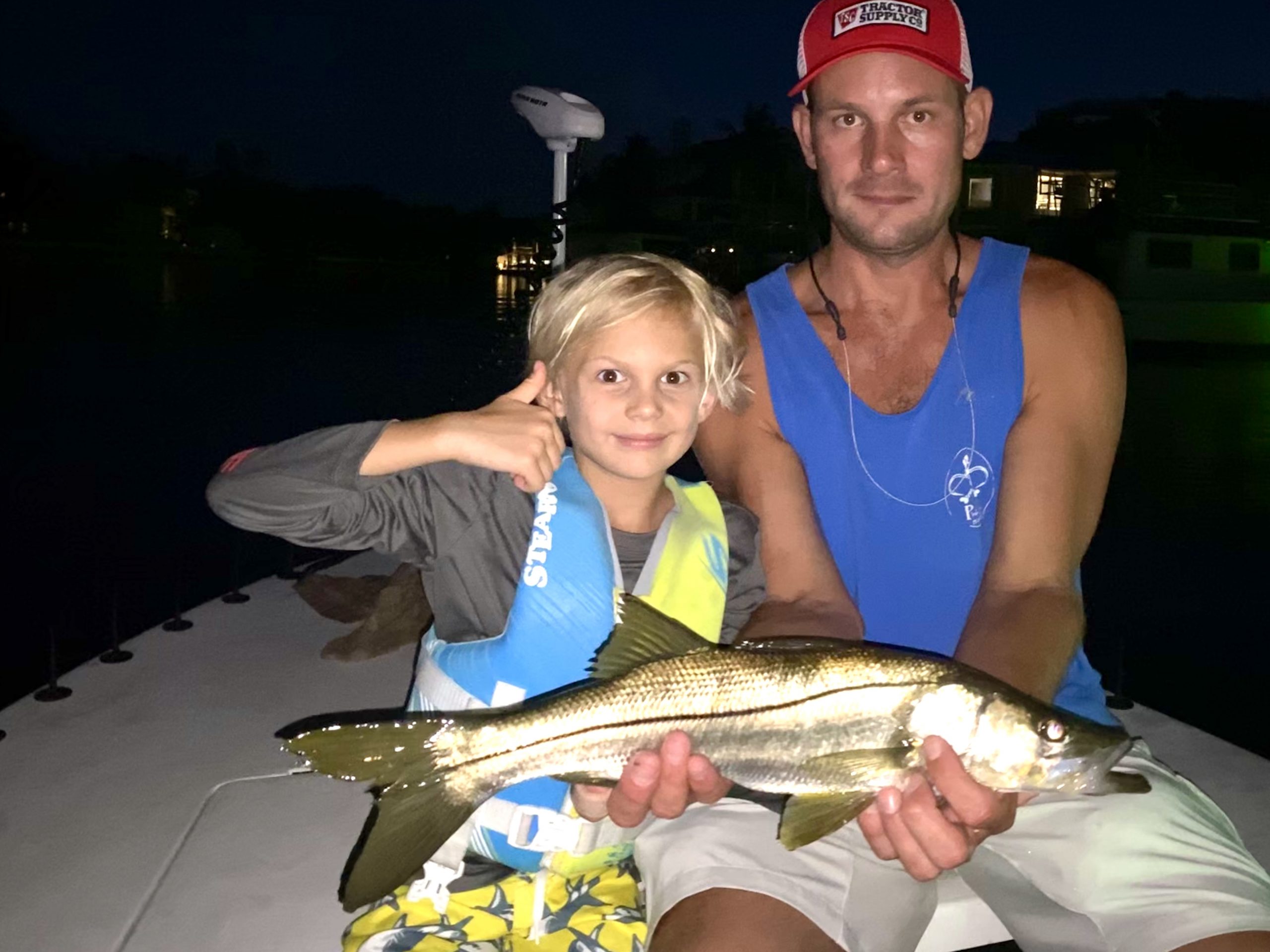 Thumbs up from a young angler and his dad while they hold a snook