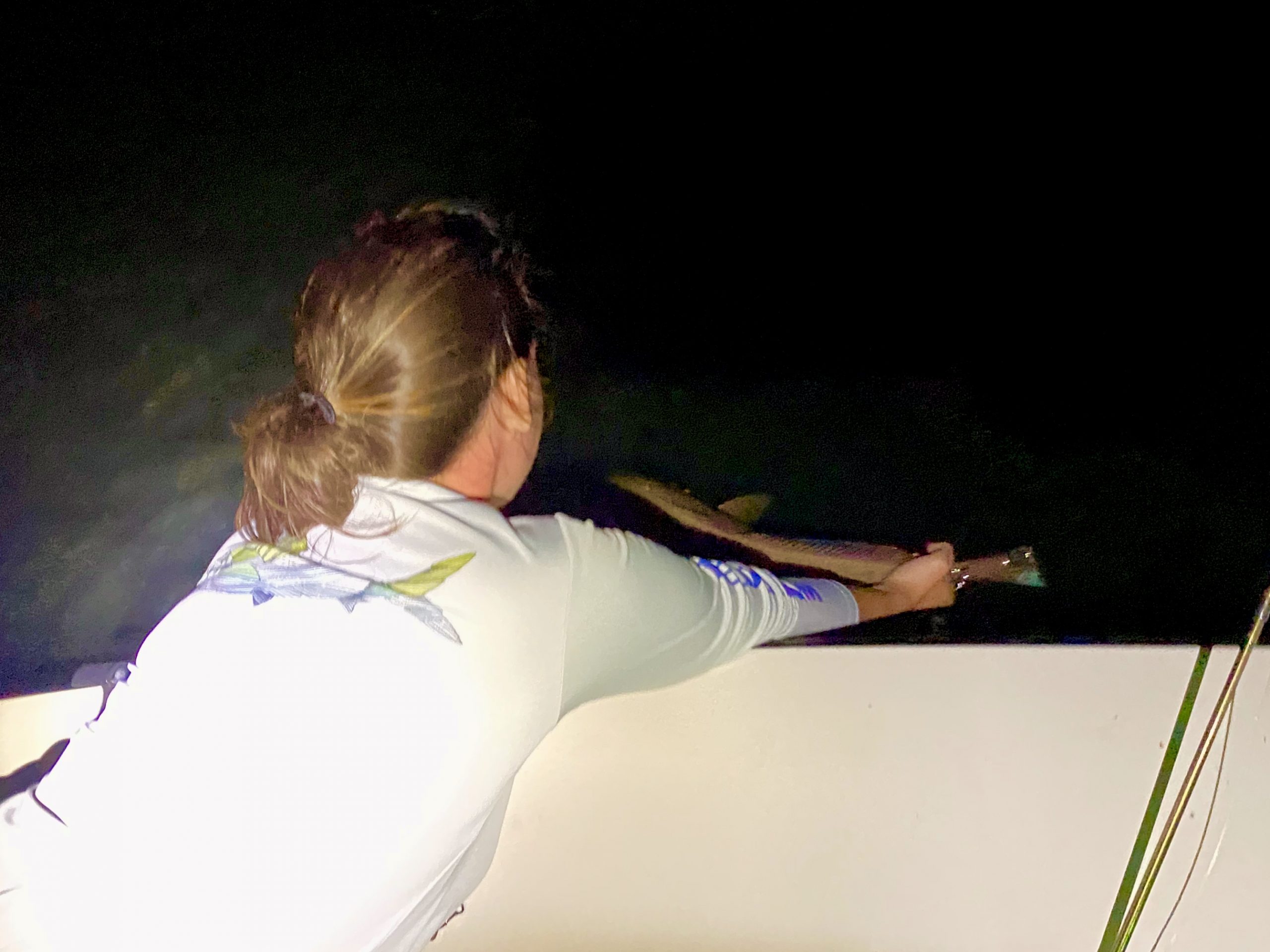 Angler releases a redfish back into the water at night