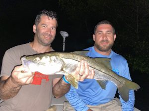 anglers hold a snook caught at night