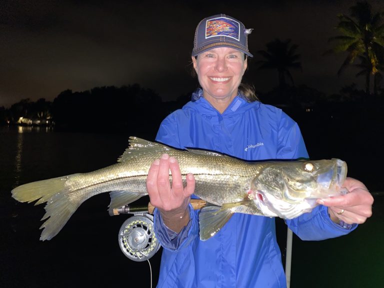 An angler holds a snook caught with a fly rod