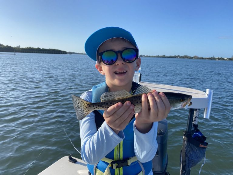 A young angler holds a speckled seatrout