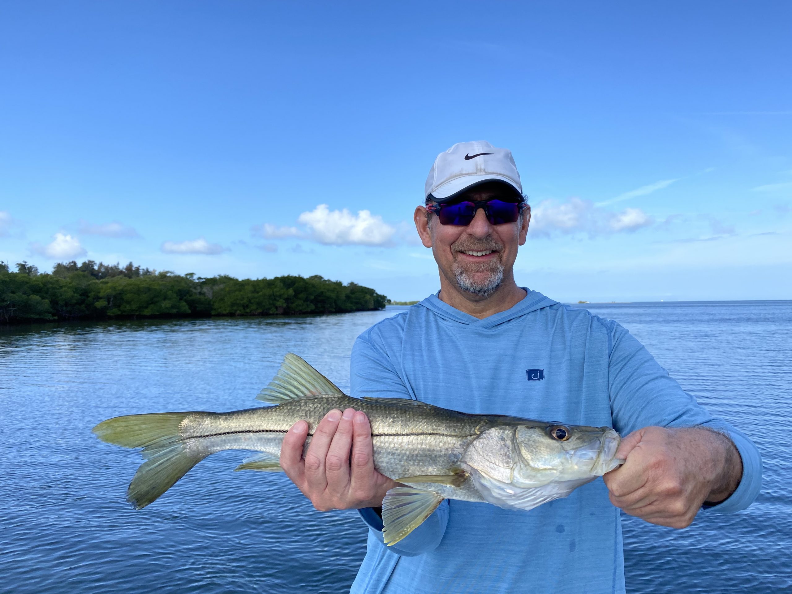 An angler smiles while holding a snook caught on a paddletail in lower tampa bay