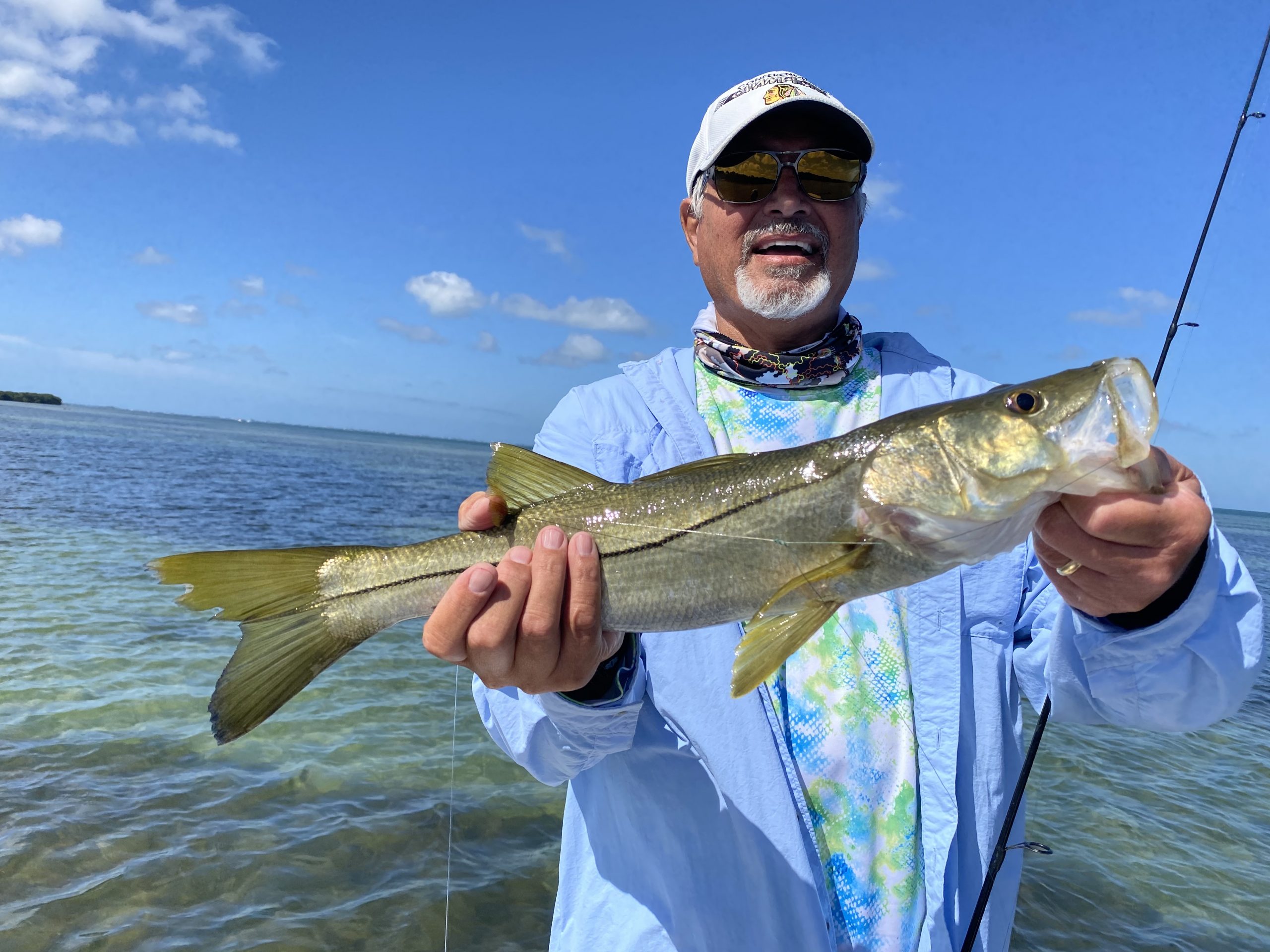 A snook caught by an angler is held out to the camera