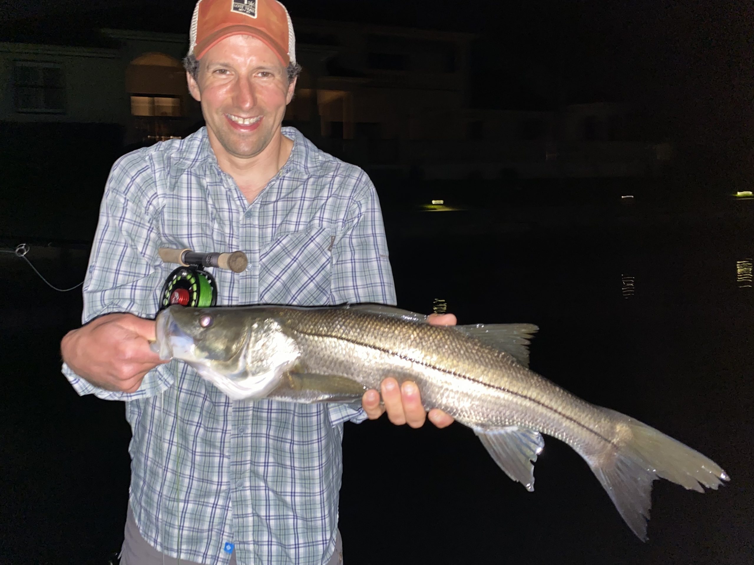 An angler holds a snook he caught while fly fishing