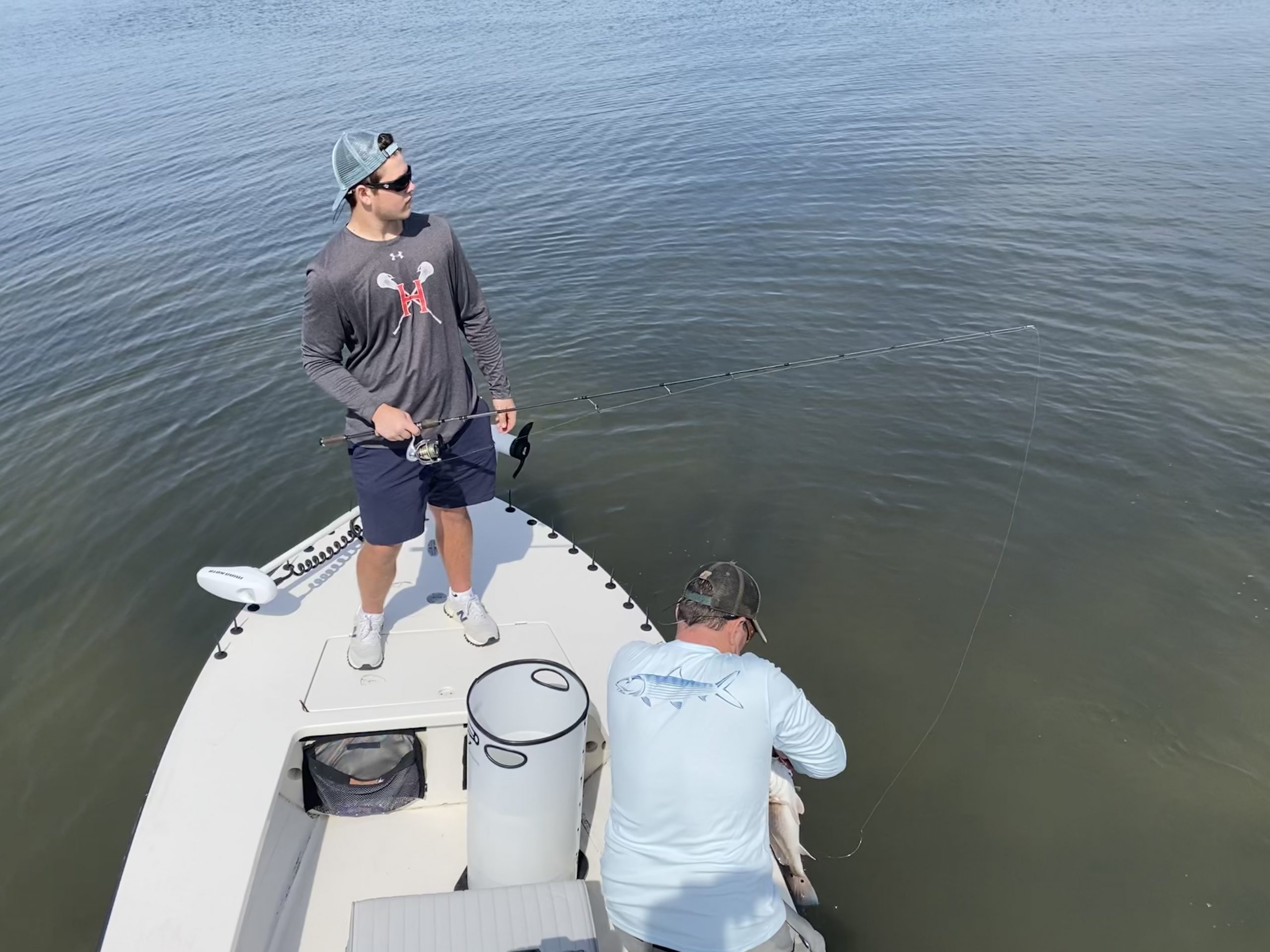 A father takes a redfish off the hook for his adult son