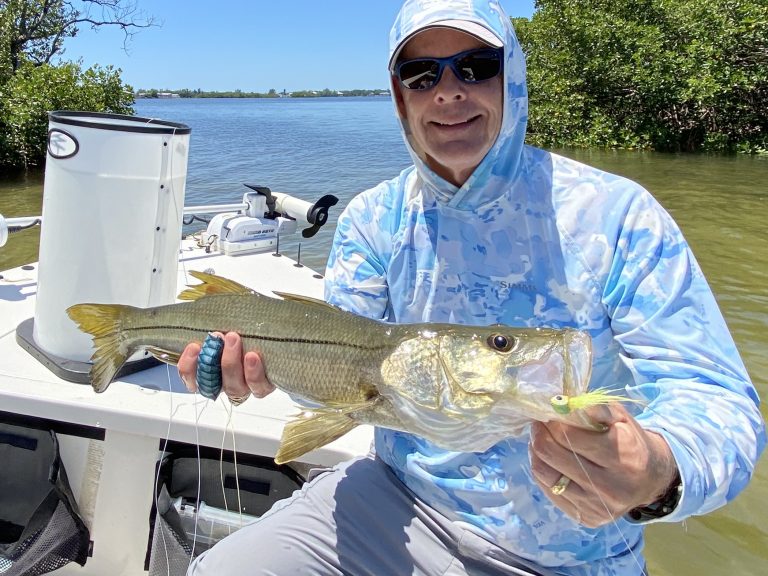An angler holds a snook he caught with a fly