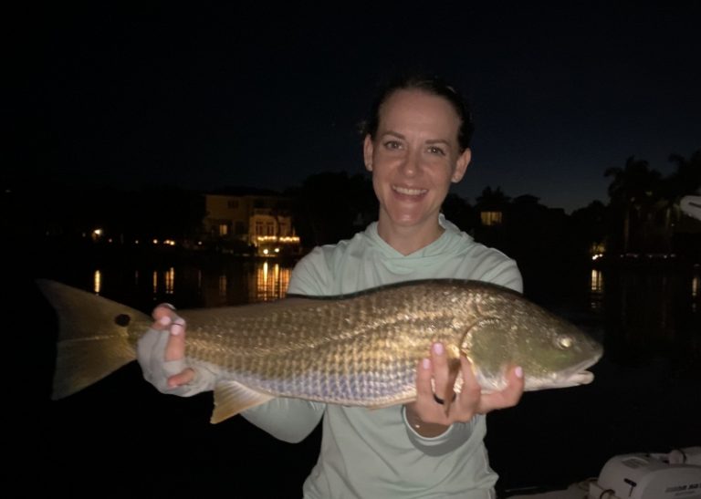 An angler smiles holding a redfish