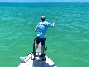 an angler holds a fly rod and casts at tarpon in the gulf