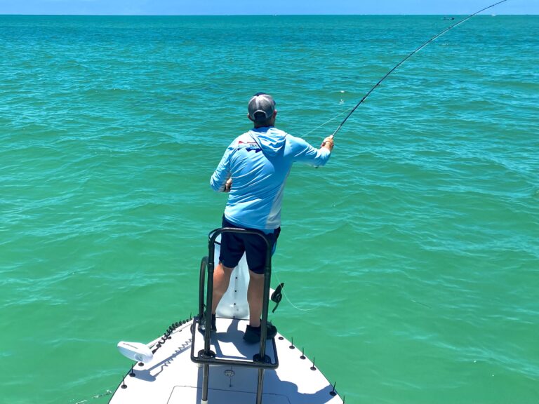 an angler holds a fly rod and casts at tarpon in the gulf