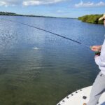 An angler holds a fishing rod and fights a redfish that he hooked while fly fishing near Tampa Bay
