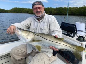 An angler holds a snook that he caught while on a fishing charter in tampa bay