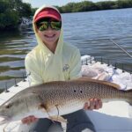 A young angler holds a nice redfish up for the camera