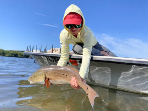 A young angler releases a redfish back into the water after catching it