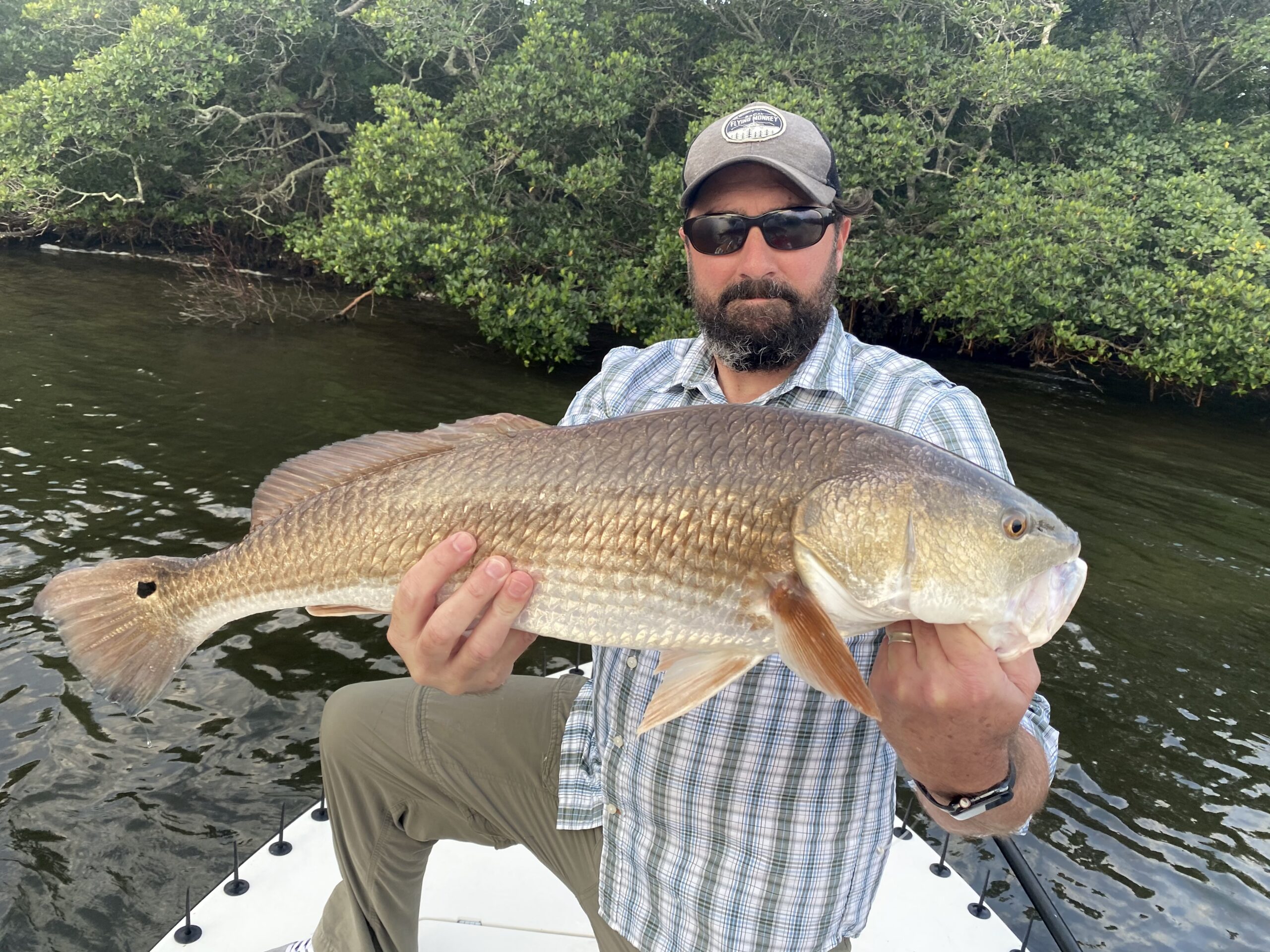 An angler holds up a chunky redfish for the camera that he caught while fishing
