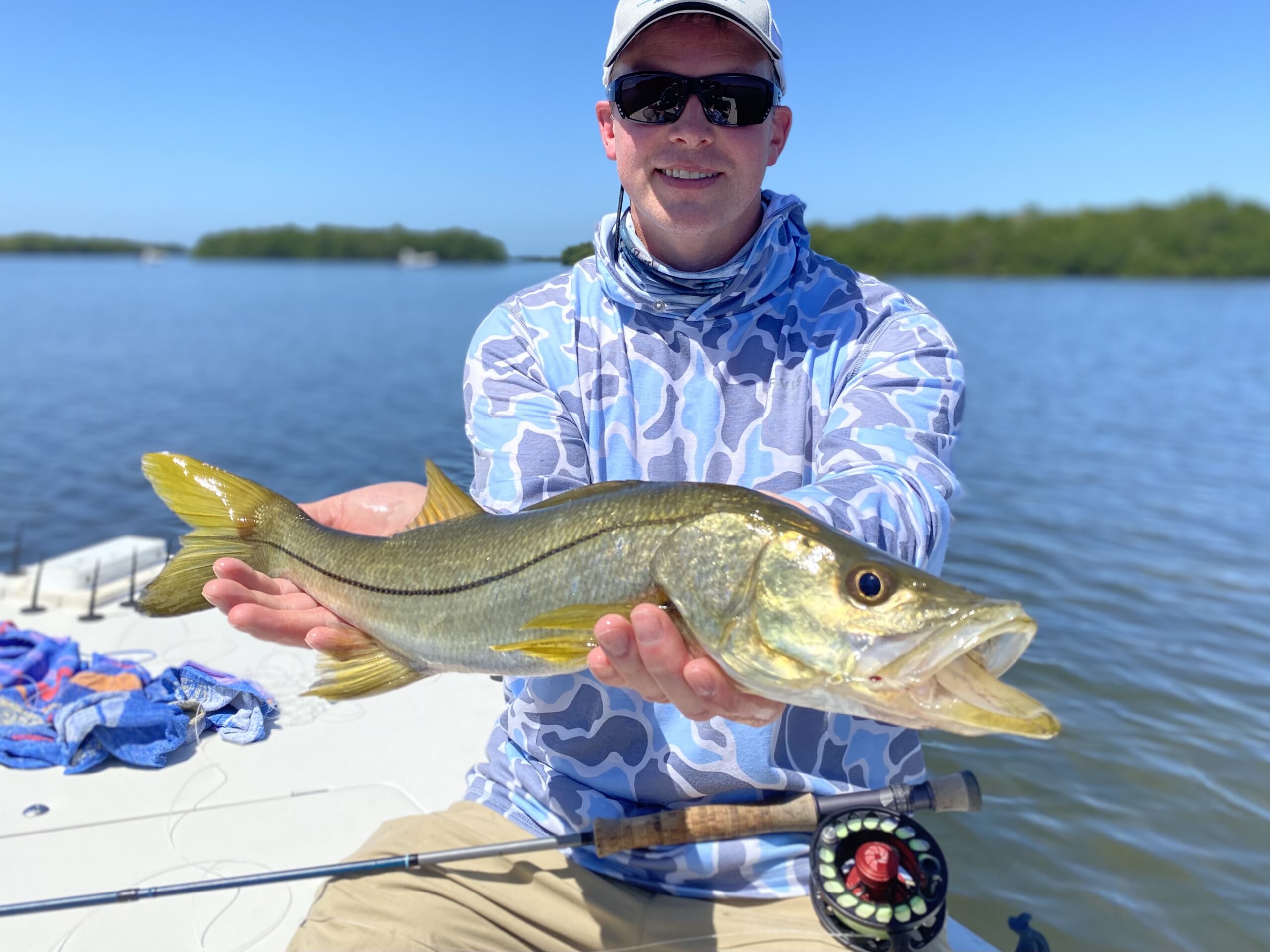 An angler holds a snook that he caught while fly fishing in tampa bay