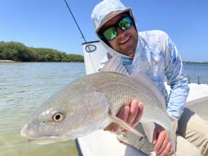 An angler holds out a redfish that he caught while fly fishing in sarasota