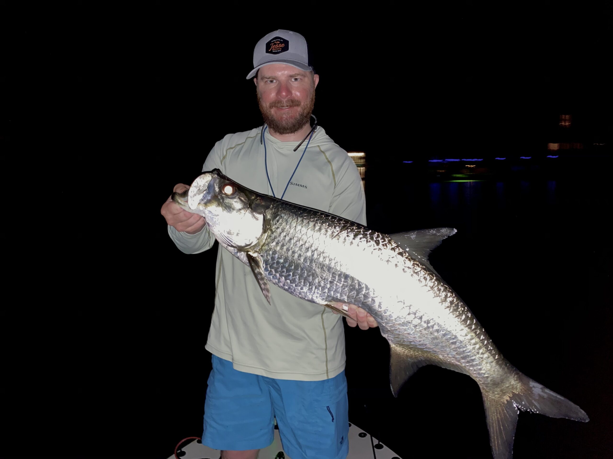 An angler holds a juvenile tarpon that he caught while fly fishing the dock lights