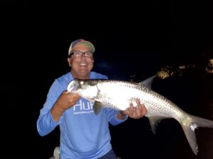 An angler smiles as he holds up his first tarpon