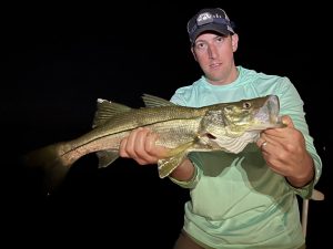 An angler holds up a snook for the camera that he caught while fly fishing