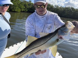 An angler holds a snook up to the camera