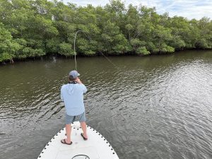 An angler fights a snook in the back country of the bow of a poling skiff