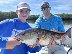 A father and son hold a redfish that was caught on artificial lures