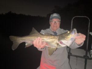 An angler holds up a big snook that he caught while fly fishing the dock lights in Sarasota, FL