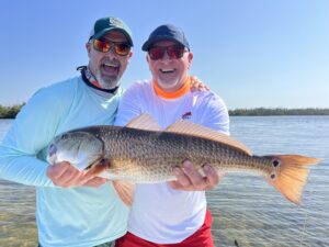 Two anglers hold a redfish up for the camera