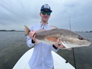 An angler holds a redfish that he caught